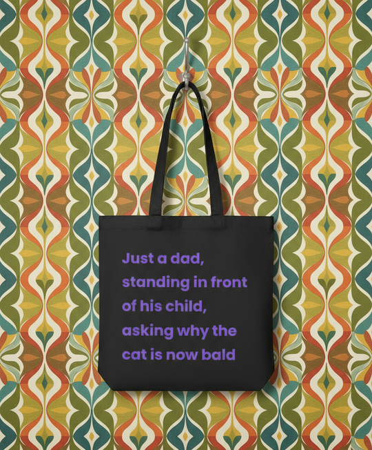 Black tote bag with purple text on a colourful patterned wall