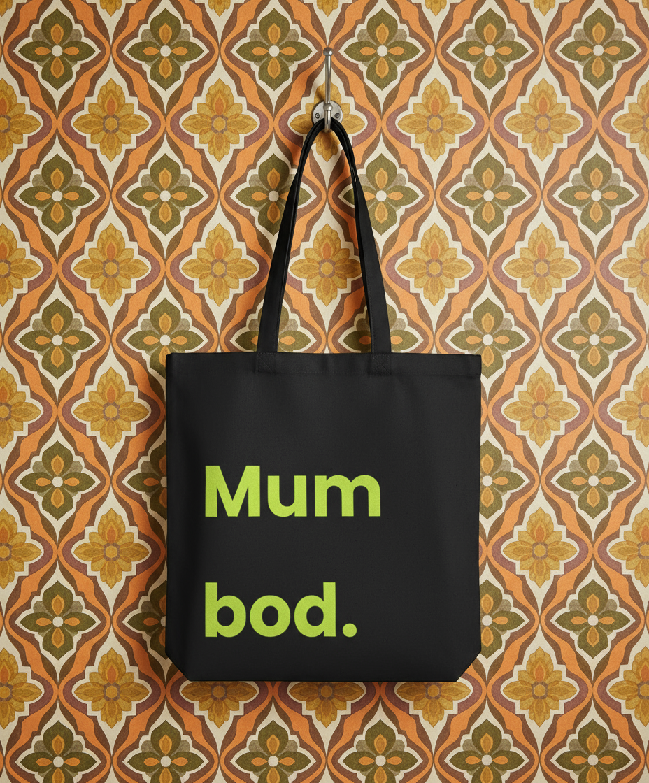 Black tote bag with 'Mum bod.' text on a patterned wall background