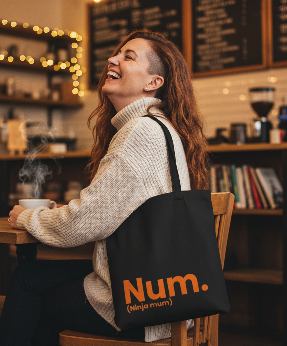 Woman sitting at a cafe with a 'Num. (Ninja Mum)' bag