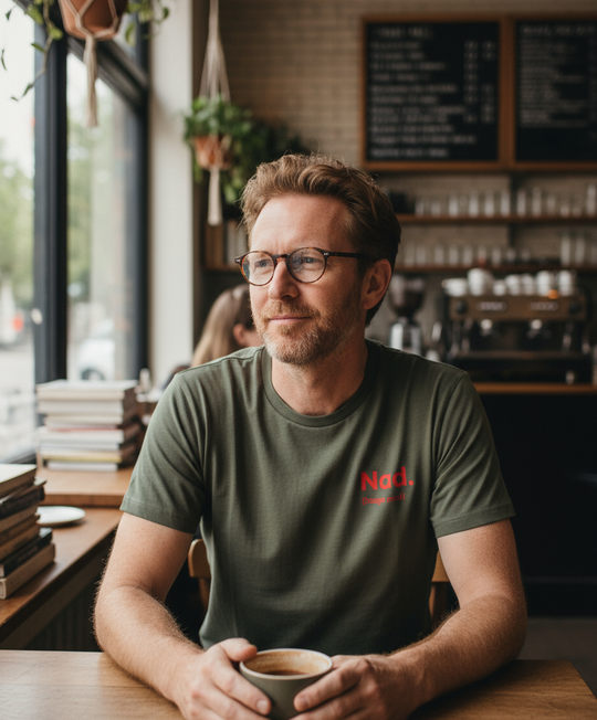 Man sitting at a table in a cafe holding a coffee cup