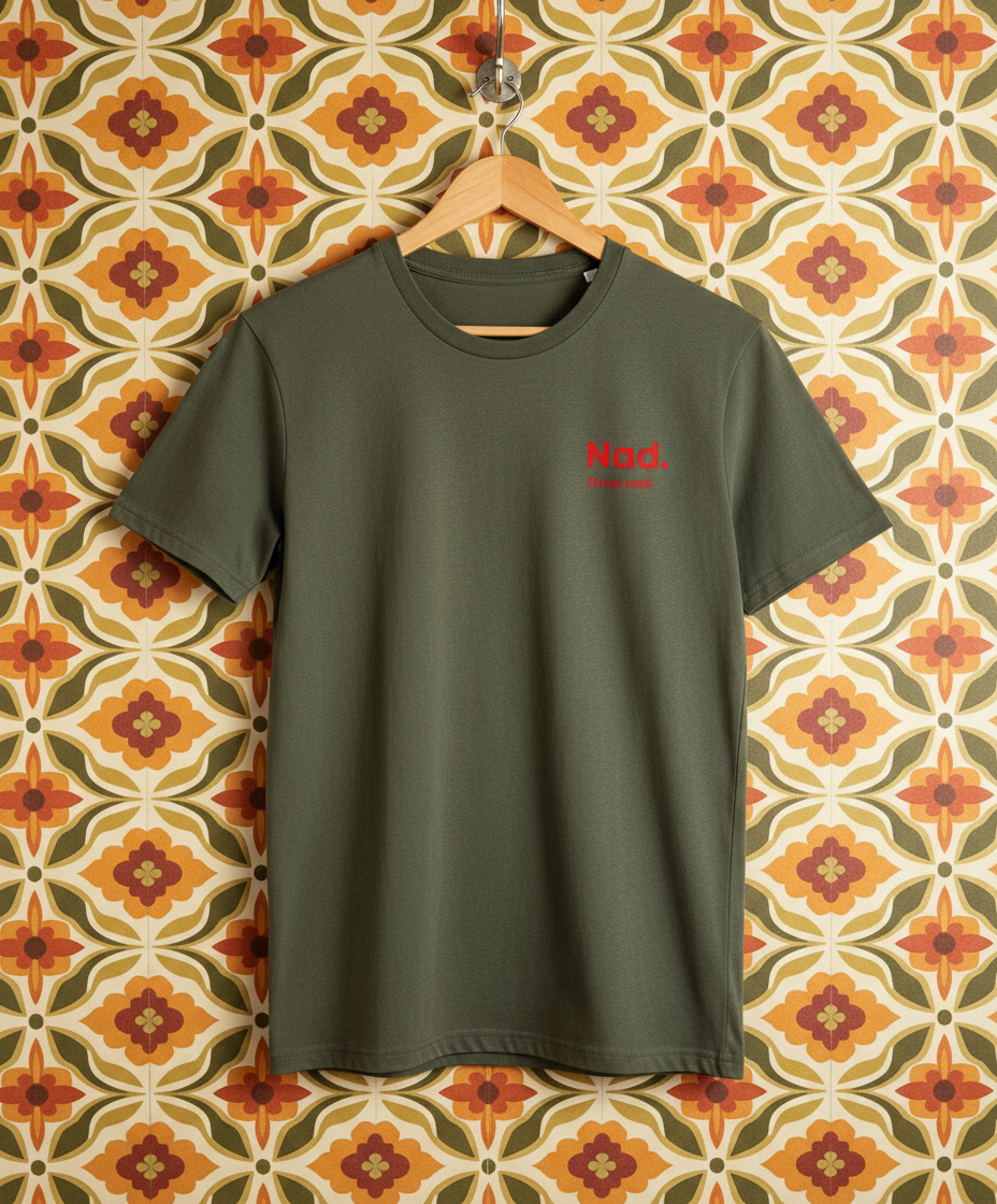 Green t-shirt with red text on a hanger against a patterned wall.
