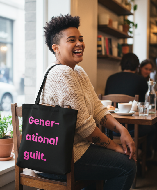Person sitting in a cafe with a tote bag labeled 'Generational guilt'.