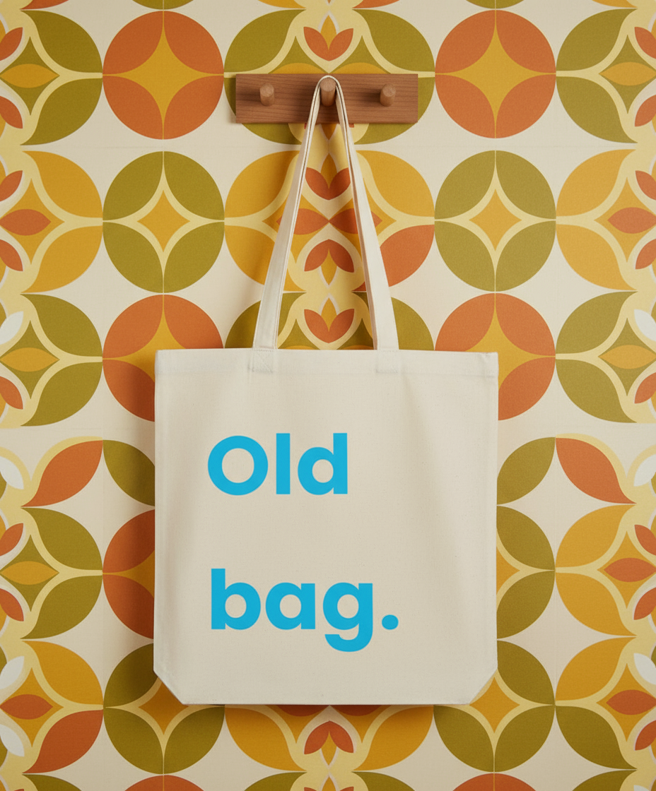 Beige tote bag with 'Old bag.' text on a colorful patterned wall