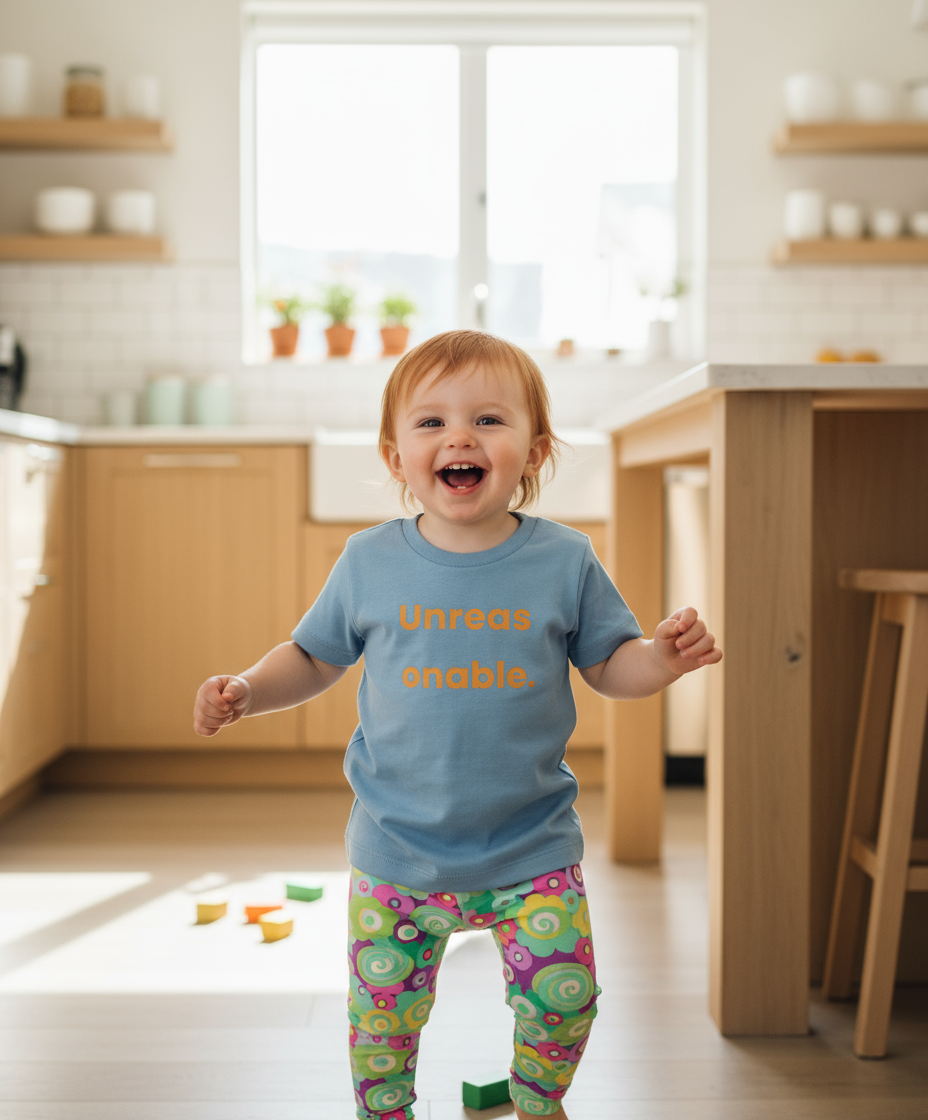 Child wearing a blue shirt with text in a kitchen