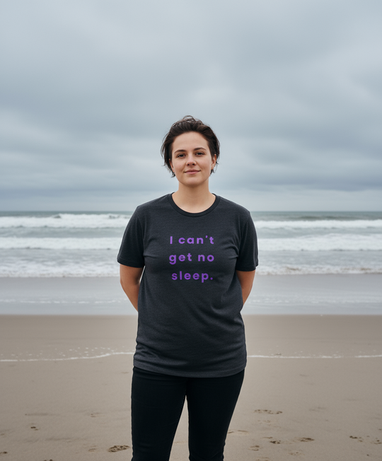 Person wearing a black t-shirt with text on a beach
