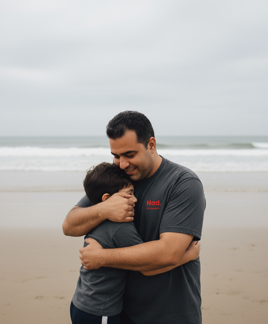 Two people hugging on a beach with a cloudy sky.