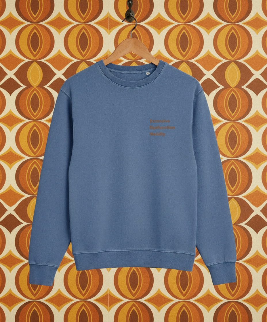 Blue sweatshirt on a hanger against a patterned wall.