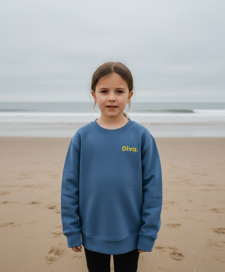Young girl wearing a blue sweatshirt with 'Diva' text on a beach