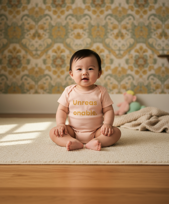 Baby sitting on a rug with a patterned wall in the background