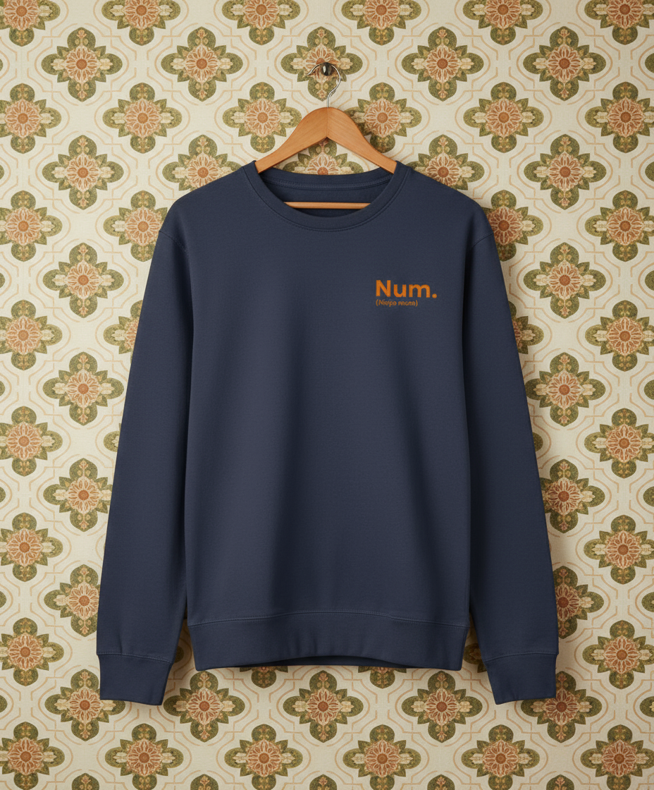 Navy blue sweatshirt with 'Num.' text on a hanger against a patterned wall.