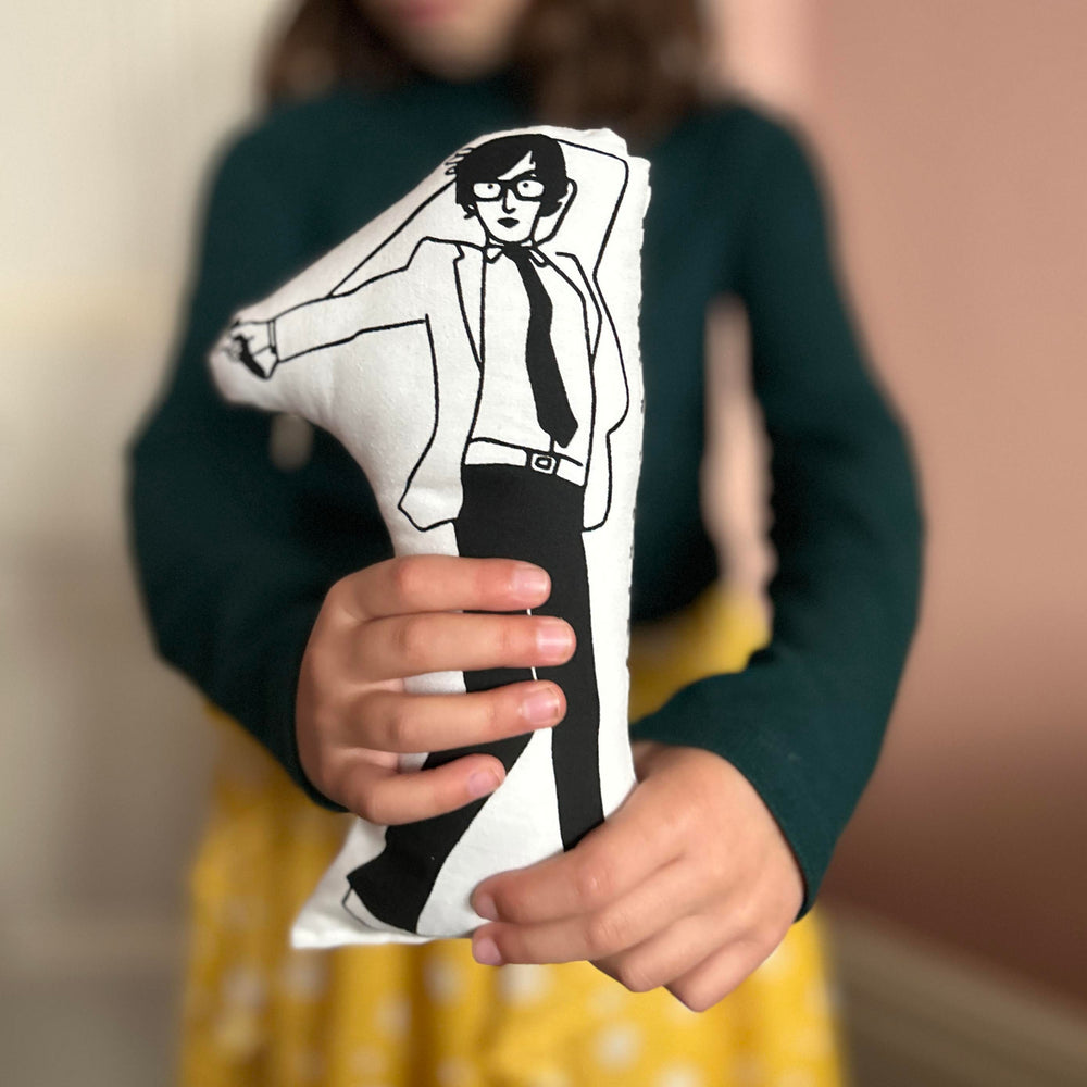 A child holding a black and white screen printed cushion doll depicting Jarvis Cocker