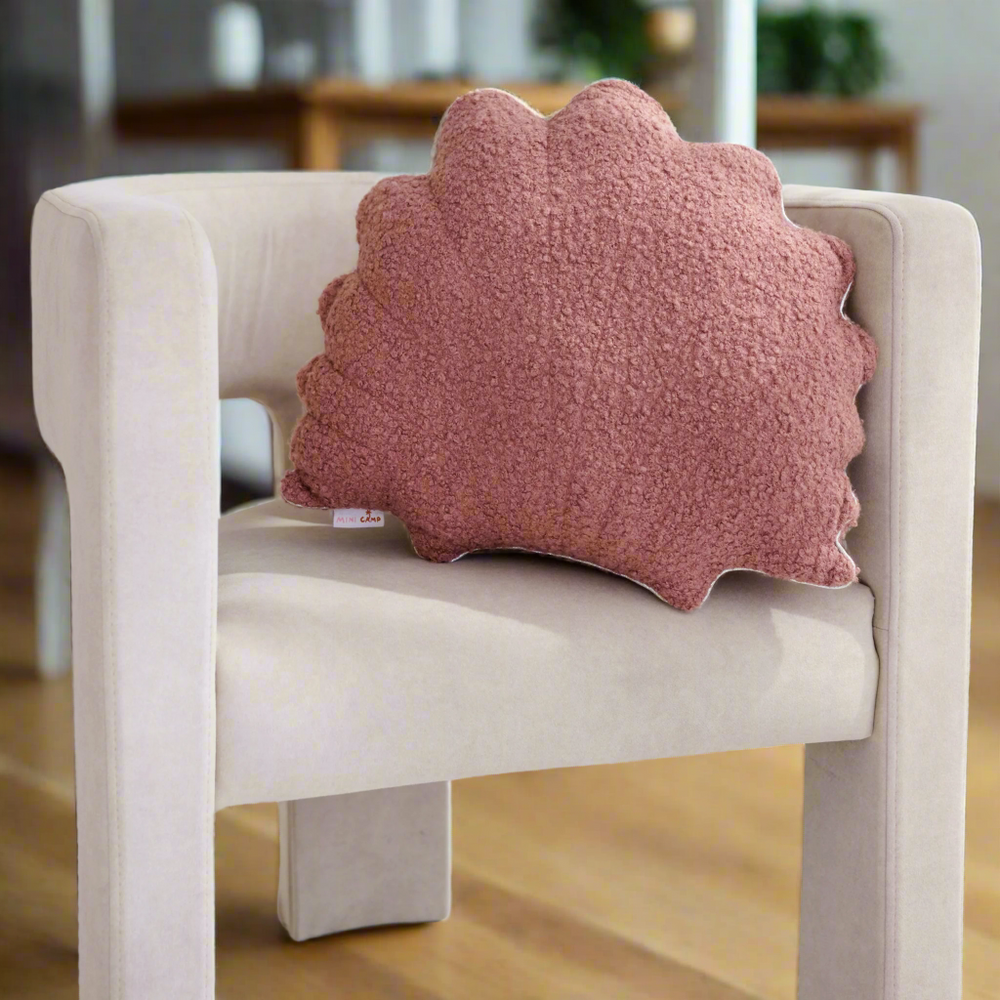 Pink textured cushion with a scalloped edge on a beige chair