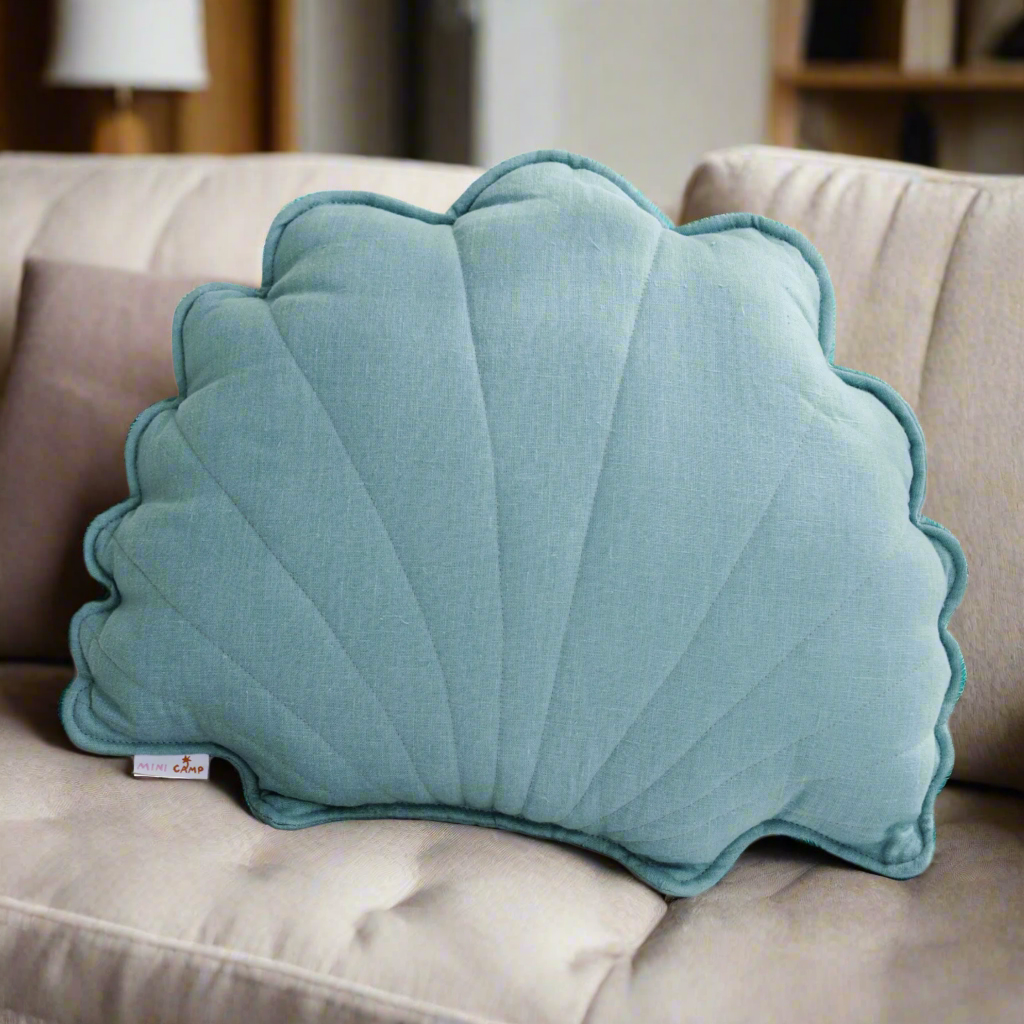 Blue shell-shaped linen cushion on a light grey sofa