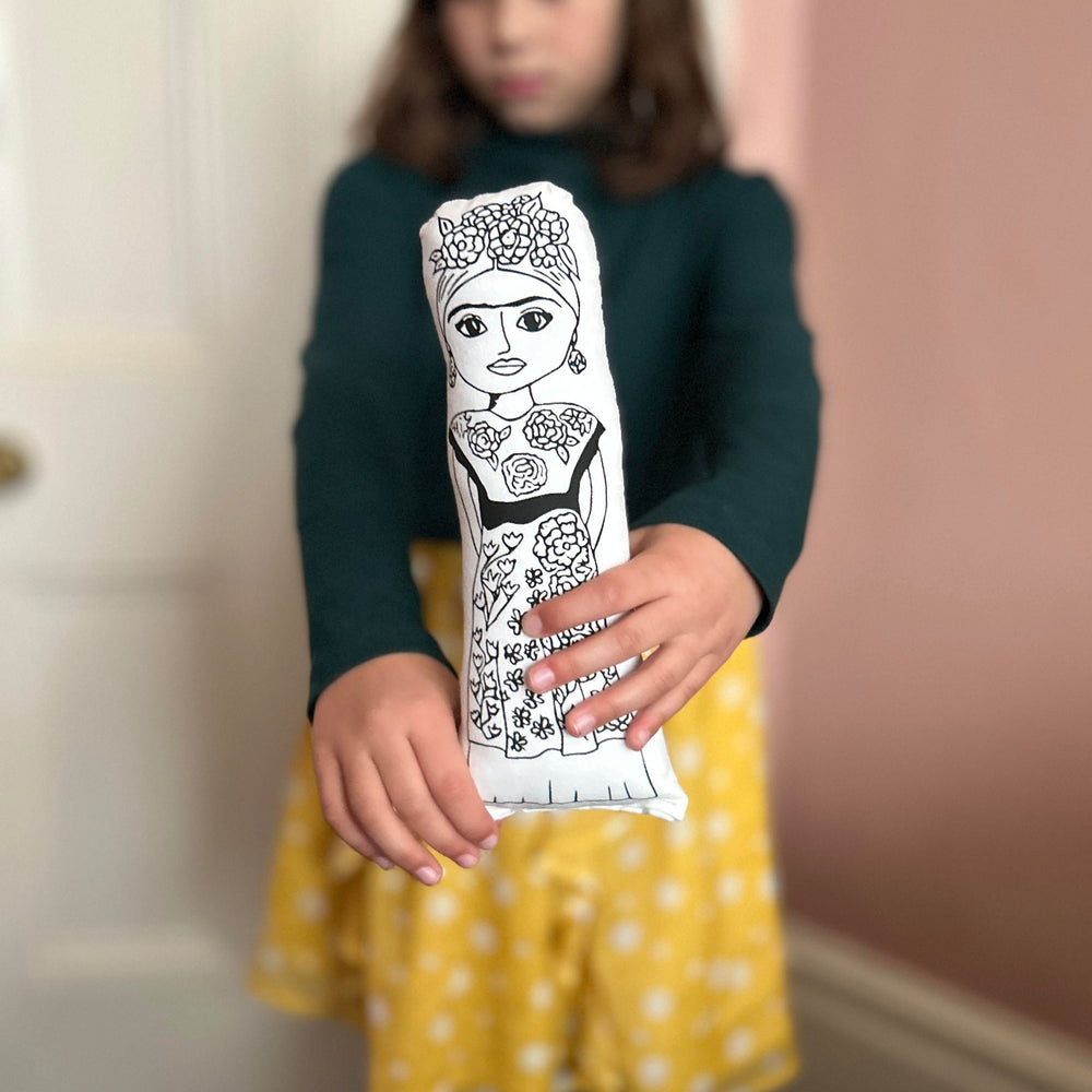 A child holding out screen printed doll cushion of Frida Kahlo towards the camera